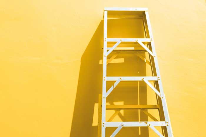 Step Ladder propped up against yellow wall